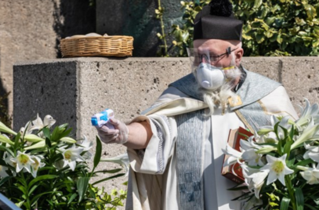 Prete benedice fedeli con la pistola d'acqua a distanza, la foto è virale