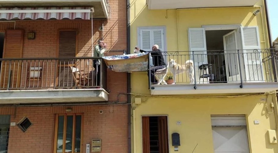 Pranzo domenicale con tavola tra un balcone e l'altro a Porto San Giorgio, lo scatto è virale
